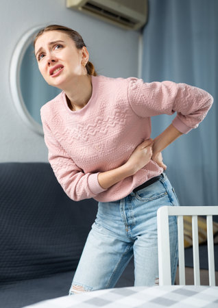 Woman suffering from back pain at homeの写真素材