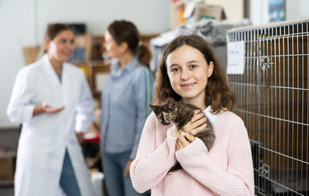 Caring preteen girl standing in animal shelter with kitten in armsの写真素材