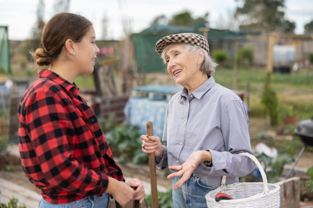 Two female gardeners talking near wooden fence in gardenの写真素材