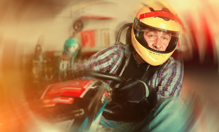 Portrait of male racer in helmet driving kart on trackの写真素材