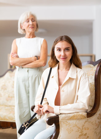 Portrait of a pretty adult woman against the background of an elderly mother in home interior