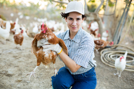 Female farmer holding chicken in poultry farmの写真素材