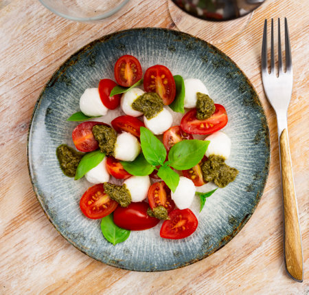 Caprese salad with tomatoes, mozzarella, basil, pestoの写真素材