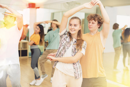 Group of teenage boys and girls training slow foxtrot movements in dance studioの写真素材