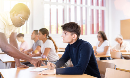 Professor explaining task solution to young man in college