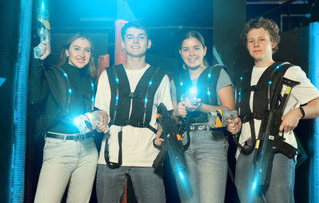 Two girls and two guys posing with lasertag guns in arenaの写真素材