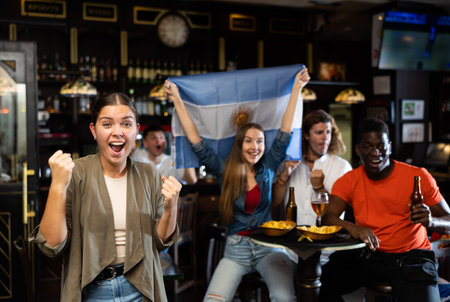 Happy girl emotionally cheering for favorite team of Argentina in sports barの写真素材