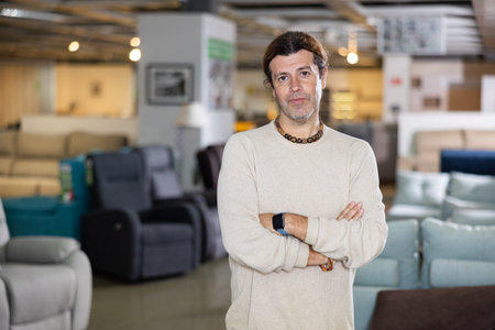 Male furniture salesperson presenting armchairs for sale in furniture showroomの写真素材