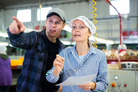 Female supervisor talking to young foreman of citrus sorting factoryの写真素材