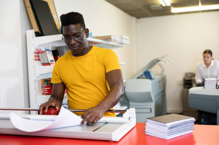 Employee of printing house checks the quality of printing in computer room