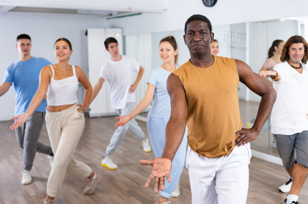 Group of different people rehearsing dance in dance studio