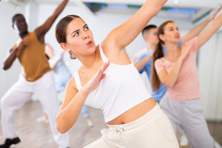 Group of sporty young adult multinational sports people making straight line with hands exercising...