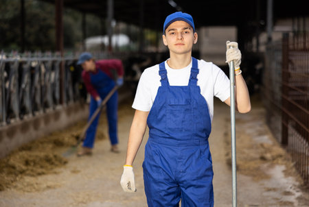 Farmer man stands with rake at cow farmの写真素材