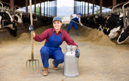 Young woman farmer with can works on dairy farmの写真素材