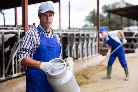 Farmer man holds milk can at cow farm