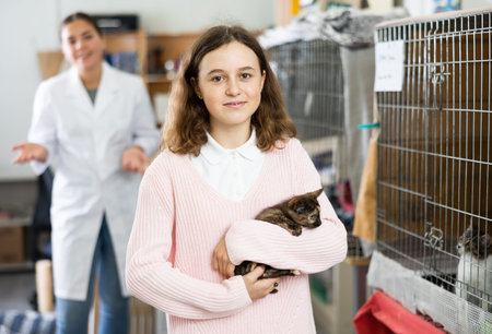 Caring preteen girl standing in animal shelter with kitten in armsの写真素材