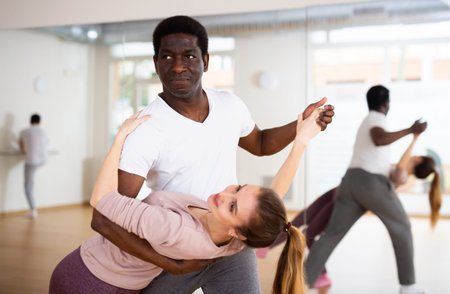 Man and woman practicing salsa moves in dancing room