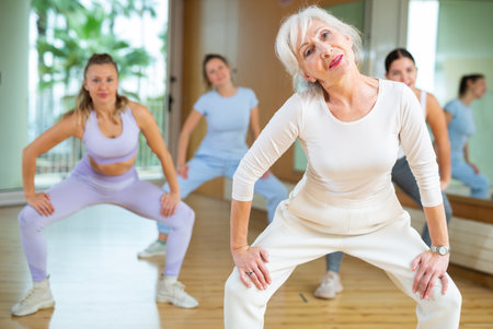 Dynamic elderly woman practicing aerobic dance in training hallの写真素材