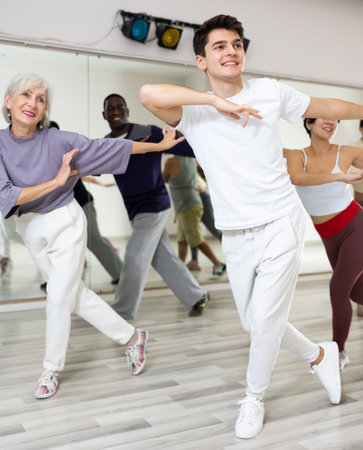 Caucasian man rehearsing modern dance with group in dance school