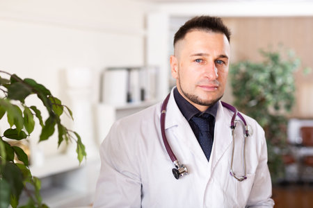 Portrait of friendly male doctor in white coat at clinic