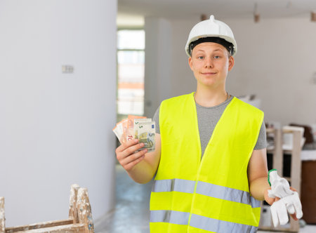 Satisfied young man with bunch of cash for part-time jobの写真素材