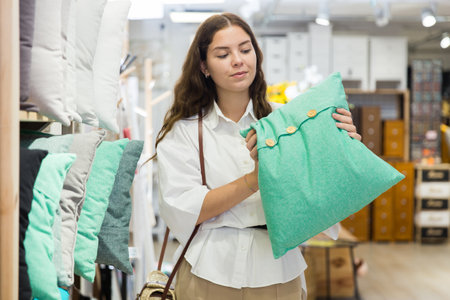 Woman choosing pillow at household goods shopの写真素材