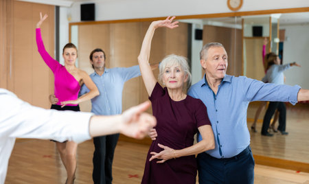 Elderly pair practicing ballroom dance in dance studio