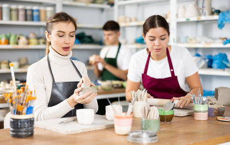 Two young women making pottery in workshopの写真素材