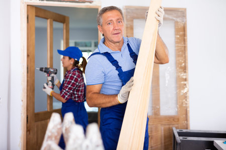 Repairman carrying bunch of wooden planksの写真素材