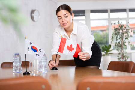 Young female attendant putting up flags for international negotiations between south korea and canadaの写真素材