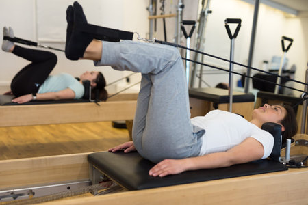Young Hispanic woman performing pilates on reformer in fitness studio