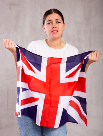 Irritated young woman with Britannic flag. Isolated on gray backgroundの写真素材