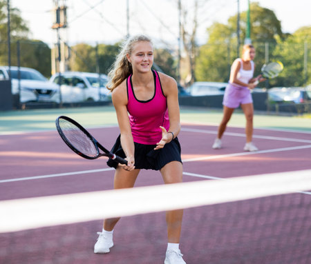Sportive woman dressed in t-shirt and skirt playing tennis with partnerの写真素材