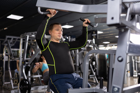 Man exercising back on pull down lever machine in gym