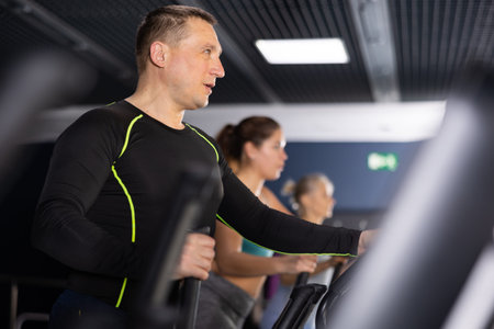 Middle aged man in the gym is engaged in sports using an ellipsoid simulator. Healthy lifestyle and...