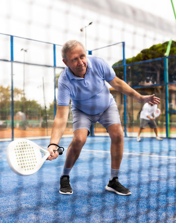 Positive mature man playing paddle tennis outdoorsの写真素材