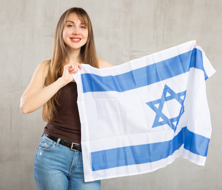 Young cheerful woman holding Israel flagの写真素材