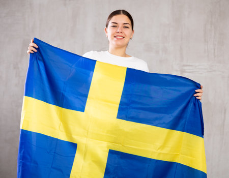 Happy girl stands with flag of Sweden. Isolated on gray backgroundの写真素材