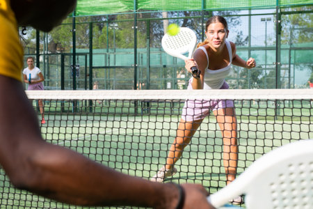 Athletic caucasian woman plays padel. View through tennis netの写真素材