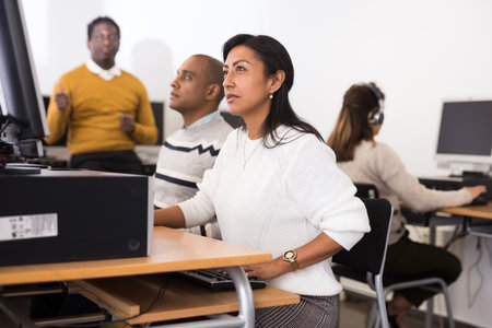 Interested hispanic woman working on computer in libraryの写真素材
