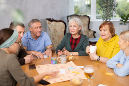 Retirees happy play board games and drink tea with cookiesの写真素材
