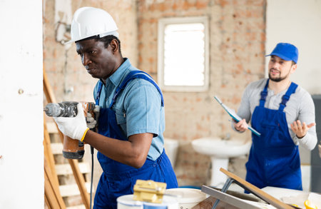 Foreman tells the builder where to drill holes with hammer drillの写真素材