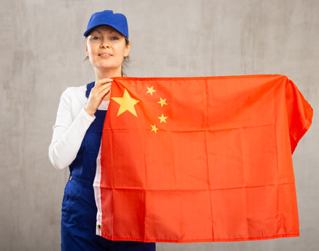 Smiling adult woman in uniform holding China flagの写真素材