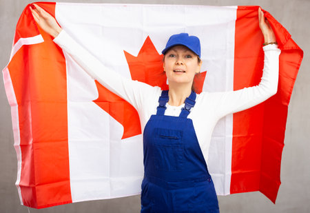 Smiling adult woman in uniform holding Canada flagの写真素材
