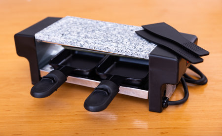 Raclette grill stands on wooden tableの写真素材