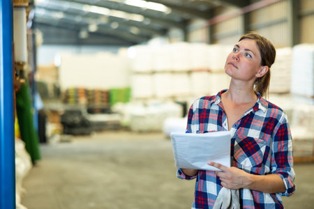 Woman inspecting warehouse to check quantity of goods on shelvesの写真素材