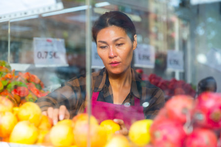 Merchandiser setting out goods in greengrocerの写真素材