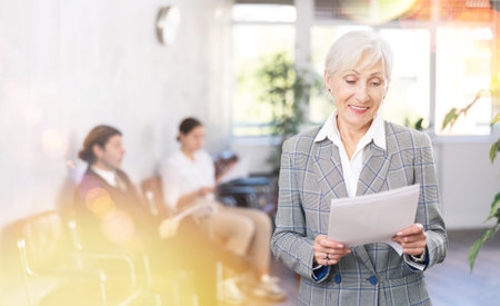 Elderly woman posing with documents in officeの写真素材