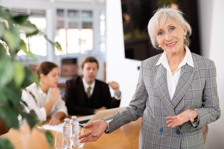 Friendly senior female entrepreneur inviting to modern officeの写真素材