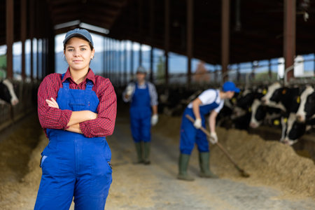 Portrait of positive female farm worker in cowshedの写真素材